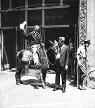 Man on donkey or burro ('Texas Centennial Exposition, Dallas, Nov. 29') in front of National Press Building, Washington, D.C. circa 1936.