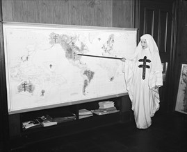 Miss Mildred Showalter of Washington, dressed as the Spirit of the Double-barred cross of the anti- tuberculosis movement throughout the world, points to various battlefronts throughout the world wher...