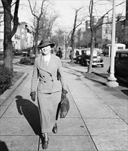 1930s woman wearing business suit walking down a city street circa December 1935.