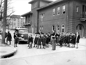 Crossing guard helping children cross the stree circa February or March 1935.