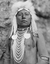 Edward S. Curtis Native American Indians - Crow Indian named Which Way, half-length portrait, facing front, wearing headdress and several necklaces circa 1905.