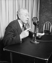 Man speaking to a radio audience via a WOL-AM radio microphone circa 1936.