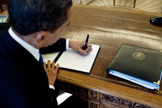 President Barack Obama writes at his desk in the Oval Office 3/3/09. .