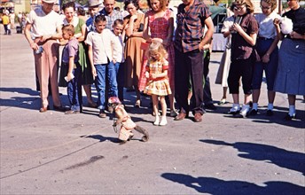 Fair goers at the Texas State Fair watch a monkey as he entertains the crowd circa 1954-1956.