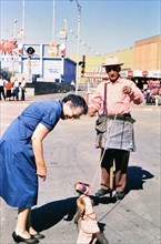 Woman looking at a small monkey at the Texas State Fair circa 1954-1956.