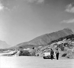 Two mexican men near a parked car just outside of Monterrey Mexico circa 1957.