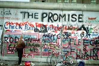 A West German woman attempts to chip off a piece of the Berlin Wall as a souvenir.   A portion of the Wall has already been demolished at Potsdamer Platz..