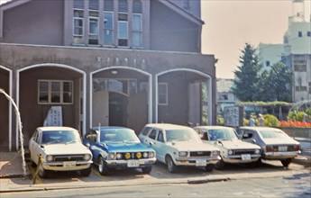 (R) Cars parked outside a church in Kanazawa Japan circa 1976.
