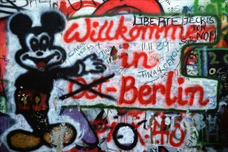 Graffiti on the west side of the Berlin Wall depicts the transition toward a unified Berlin. .