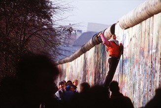 A West German man uses a hammer and chisel to chip off a piece of the Berlin Wall as a souvenir.  A portion of the Wall has already been demolished at Potsdamer Platz..