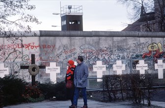 Following Germany's reunification, a couple reads grave markers of East Germans who died in an effort to escape over the Berlin Wall to the West..