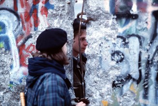 A West German girl speaks with an East German guard through an opening in the Berlin Wall..