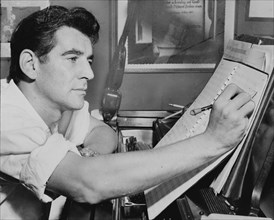 American conductor Leonard Bernstein writing music