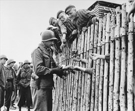 Larry Matinsk puts cigarettes into the extended hands of newly liberated prisoners