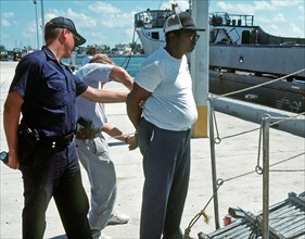 Member of a Coast Guard boarding team places a man under arrest