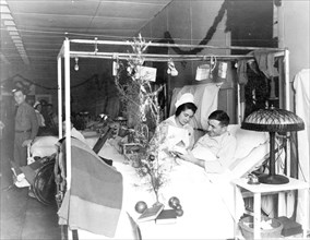 Red Cross nurse alongside of soldier in hospital bed