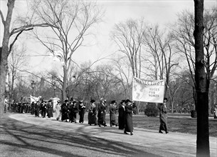 Woman suffragettes marching to the White House holding banners