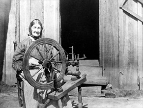 Mountain woman sitting behind her spinning wheel