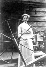 Mountain woman standing behind her spinning wheel
