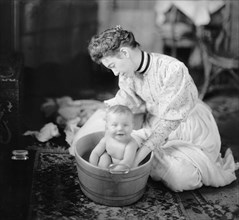A mother giving her baby a bath in the early 1900s.