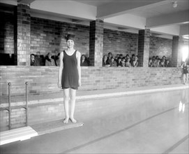 Young woman standing on diving board at a Y.W.C.A. pool