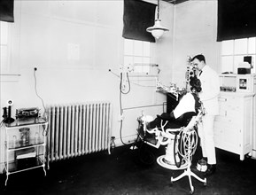 Patient and dentist inside early 1900s dental office.