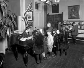 Children and librarian in an early 1900s library.