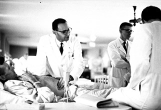 Physician examining a patient at bedside.