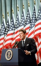 President Reagan speaking in front of American Flags.