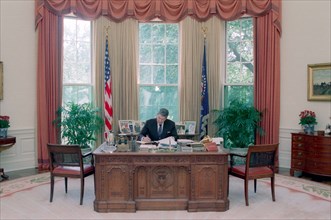 President Reagan working at his Oval Office desk.