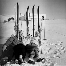 Three skiers chilling on snow, enjoying the sun in f