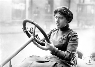 Woman sitting behind a steering wheel ca. 1910