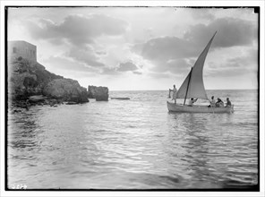 Caesarea, Israel in the 1930s, (Kaisarieh). Sunset scene with men in a fishing boat (castle on left, silhouetted) ca. 1938