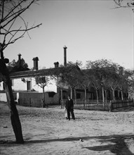 Boy and shy girl in front of building in Israel ca. between 1898 and 1934