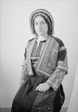 Woman in finely embroidered Ramallah costume, seated, ca. unknown date