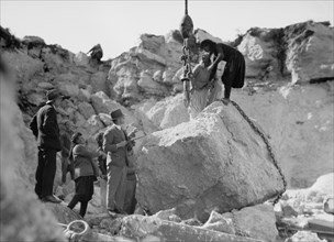 Construction of the Haifa harbour. Workers in the Athlit quarries. Crane raising a huge boulder ca. 1920
