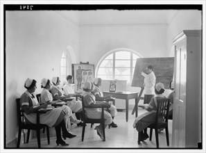 Teacher pointing to chalk board at Scots Mission Hospital in Tiberias Israel. Hospital nurses in class instructed by Dr. Little. ca. between 1934 and 1939