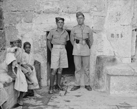 British soldiers in doorway of Church of the Nativity in Bethlehem, children sitting on left side ca. 1939