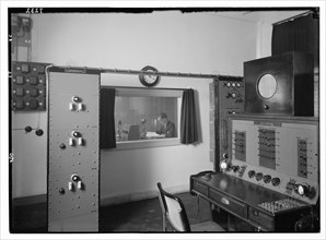 Radio studio. Control room, looking into the studio where an announcer is broadcasting ca. between 1934 and 1939