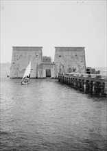 View of 1st pylon of Temple of Isis, Philae, looking North, sailboat in image ca. 1900