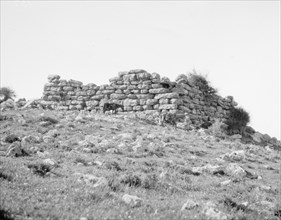 A man with a horse looking at the ruins of a prehistoric flint castle near Wady Seir ca. 1900