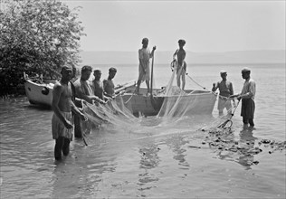 Tiberias fisheries, Arab men fishing with a drag net. Loading drag net on boat ca. 1940