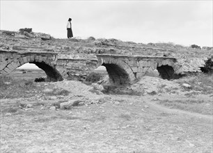 (Kaisarieh)  Man standing on top of a Roman aqueduct which once brought water to Caesarea from Nahr-es-Zerka & Springs of Miamas ca. 1938