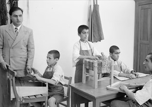 Children at the blind school in Hebron. In the handicraft room, straw & raffia work ca. 1940