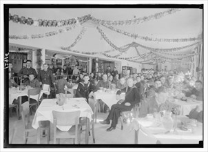 Christmas decorations in the YMCA hostel dining hall, military personel sitting at tables Dec. 1943