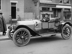 James Kelly driving an automobile, facing left, ca.  between 1910 and 1935