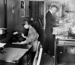 Man and woman working in an accountant's Office, woman typing ca.  between 1910 and 1920