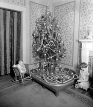 Early 20th century Christmas tree in a living room, children looking at toys ca. between 1910 and 1935
