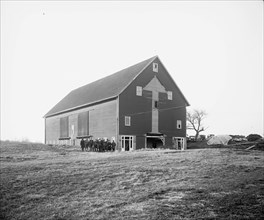 Men and women standing outside a barn  ca.  between 1910 and 1926