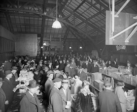 Men and women attending a dead letter sale being held in a gymnasium ca.  between 1910 and 1925